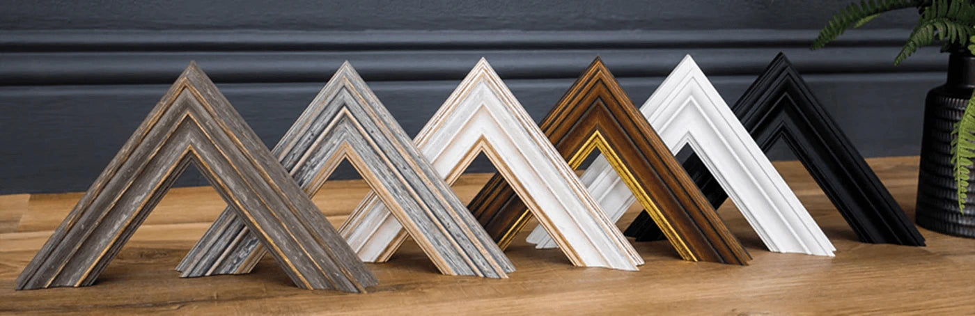 Six Picture Frame Corners place one after the other on a wooden surface.