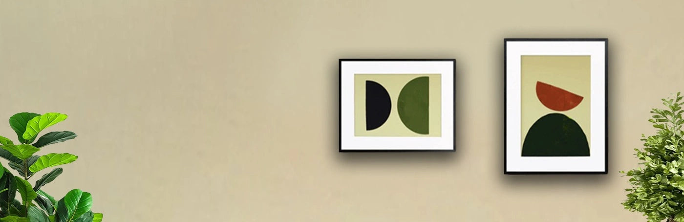 Two Picture frames are hanging on a wall with decorative plants place near it.